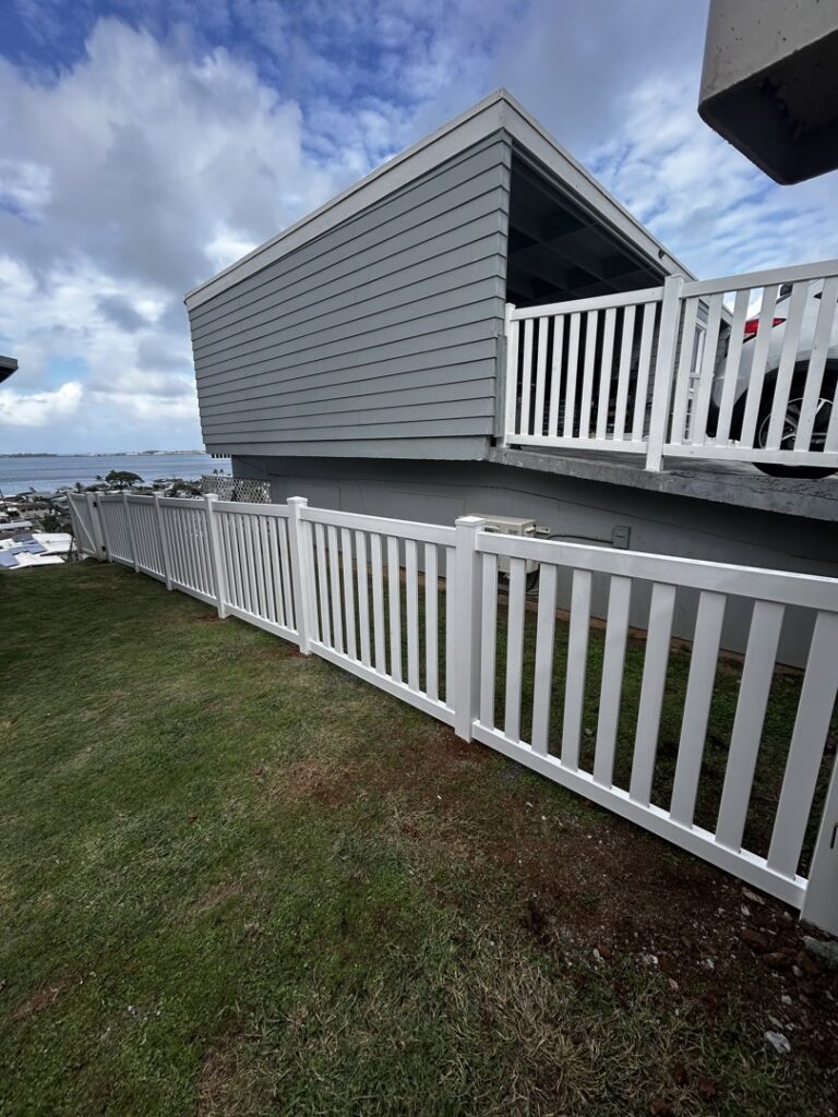 A long white vinyl fence installed along a sloped residential yard by Redmond Valleywide - Hawaii's Fence Company in Kapolei, HI
