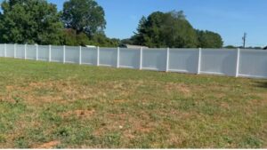 A long, clean white vinyl privacy fence installed in a spacious field by Cavitt Fencing in Concord, NC.