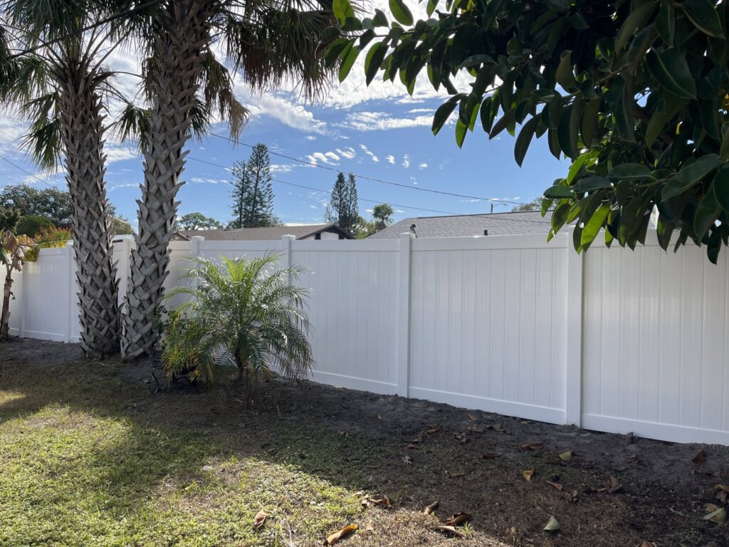 A long white vinyl privacy fence installed along a property line by Elite Fence and Outdoor of Tampa Bay in Tampa, FL.