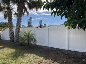 A long white vinyl privacy fence installed along a property line by Elite Fence and Outdoor of Tampa Bay in Tampa, FL.