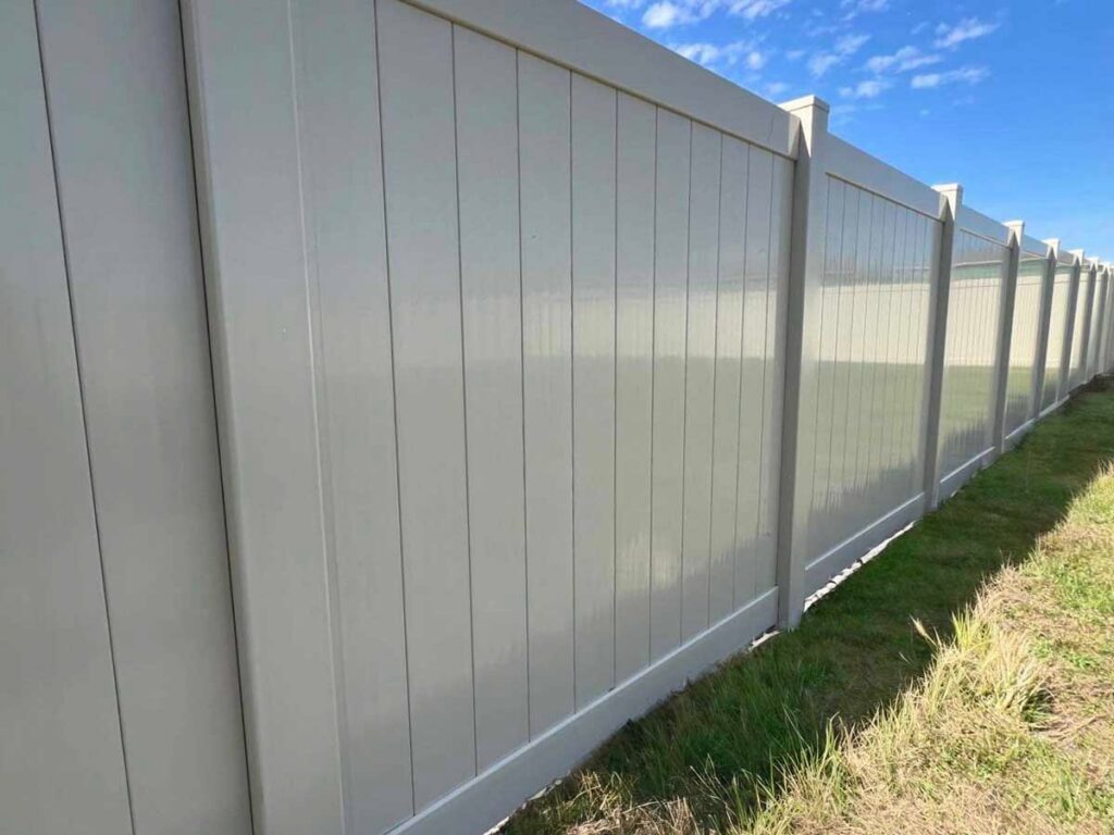 A long white vinyl privacy fence installed along a property line by Golden Eagle Fencing in Tampa, FL