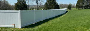 A long white vinyl privacy fence installed in a green field by KY Fencing Unlimited in Louisville, KY.