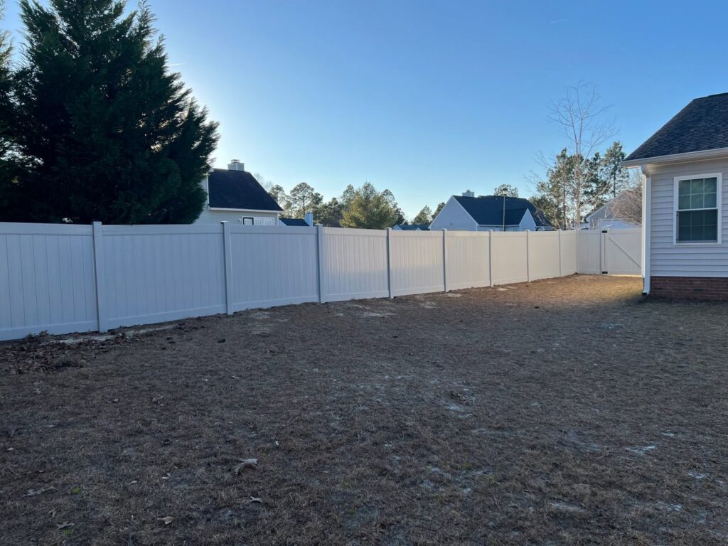 A long white vinyl privacy fence with a gate installed by JB Nealy Fence in Elgin, SC.