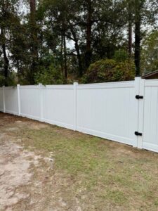 A long, newly installed white vinyl privacy fence along a property line by JBunlimitedfencingllc in Savannah, GA.