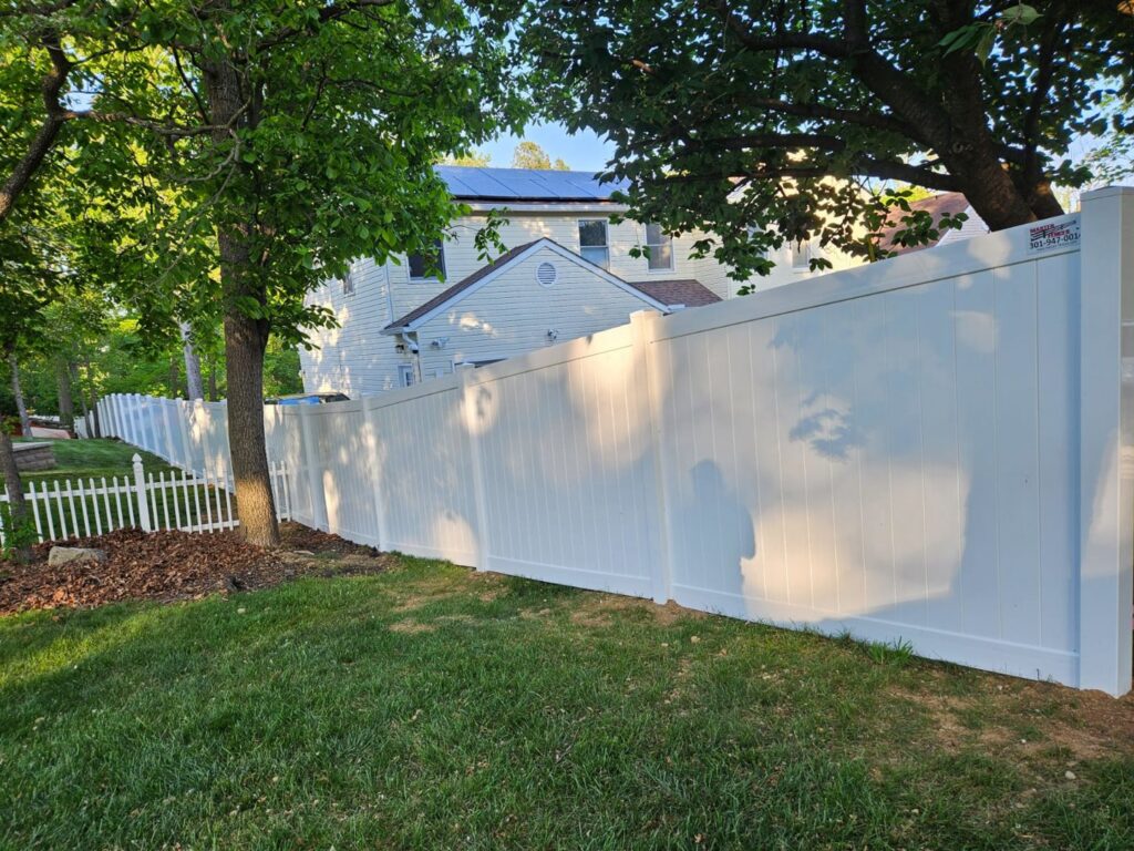 A long white vinyl privacy fence installed along a property line by Master Fences in Gaithersburg, MD.