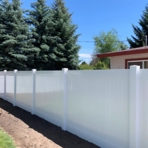 A long section of a newly installed white vinyl privacy fence running alongside evergreen trees by Performance Fencing in Rigby, ID.