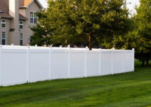 A long white vinyl privacy fence installed in a residential backyard by Fence Company of Rhode Island in Providence, RI.