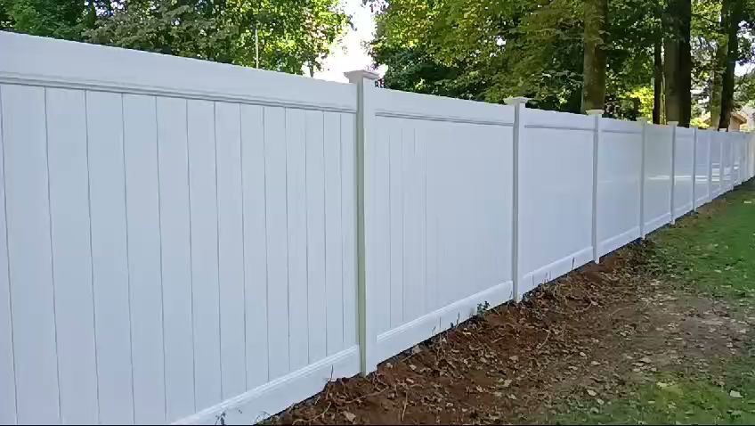 A long stretch of white vinyl privacy fence providing security for a residential property by Zelaya Fence in New York City, NY.