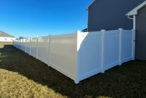 A long, pristine white vinyl privacy fence installed alongside a residential home by Smith & Company Custom Fence LLC in Niles, MI.