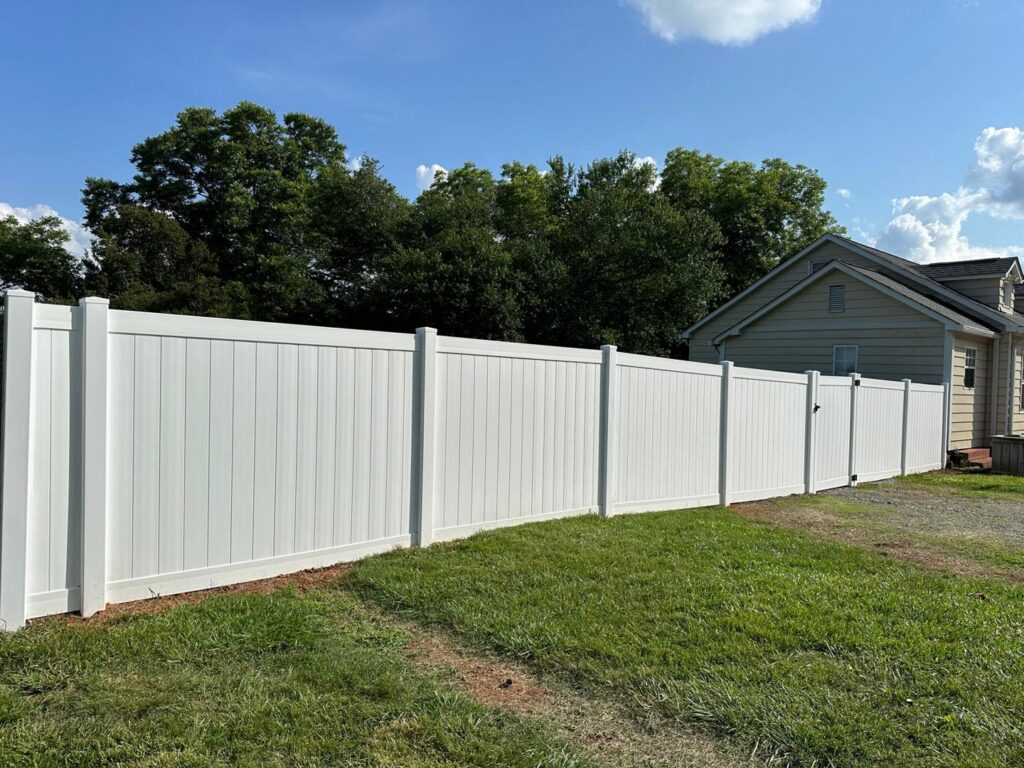 A long white vinyl privacy fence installed next to a residential home by Sunrise Fences in Monroe, NC.