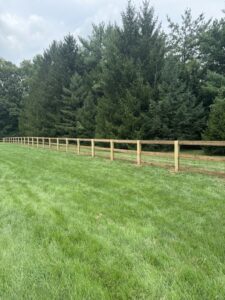 A long stretch of new wood and wire mesh fence in a large grassy field, installed by ReliableFencing in Columbus, OH.