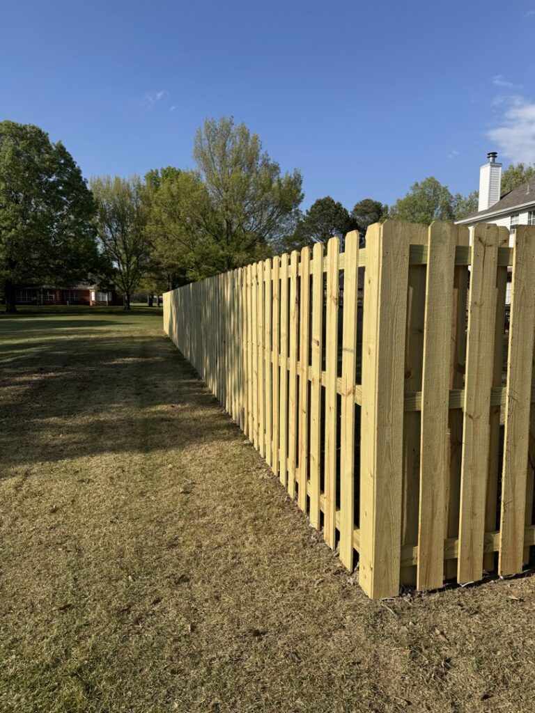 A long, newly installed wood fence in a spacious backyard with mature trees by Faithful Fencing LLC in Batesville, AR.