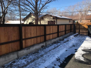 A long, dark-stained wood fence with a concrete base, installed by Red Dirt Fencing and Woodwork, LLC in Fountain, CO.