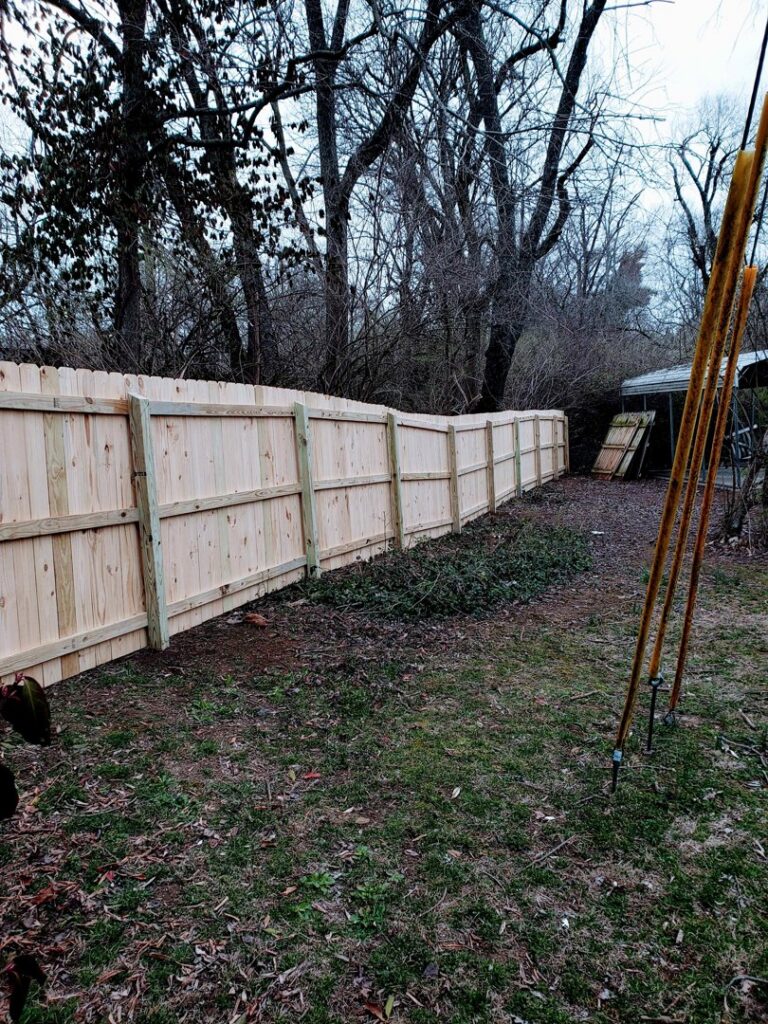 A long section of newly installed wood fence in a wooded backyard by Veteran Fence in North Royalton, OH.