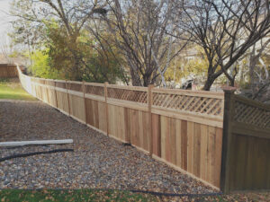 A long wood fence with a decorative lattice top installed on a sloped property by MN Mike's Fence and Repair in Lakeville, MN.