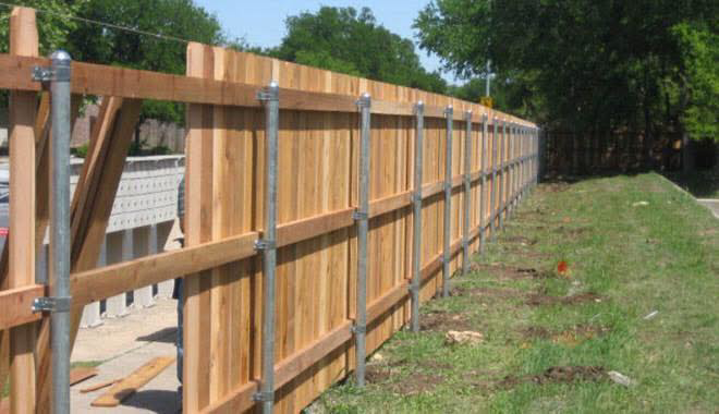 A long wooden fence with sturdy metal posts installed by Fence Innovations, serving properties in Norman, OK.