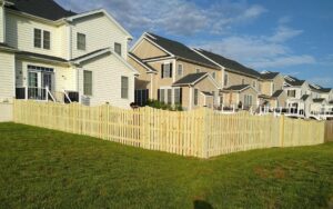 A long wooden picket fence installed in a residential neighborhood by Universal Fence LLC in Drainesville, VA.