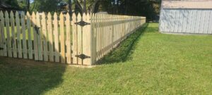 A long section of newly installed wood picket fence with a gate, completed by Fast Fences LLC in Northfolk, VA.