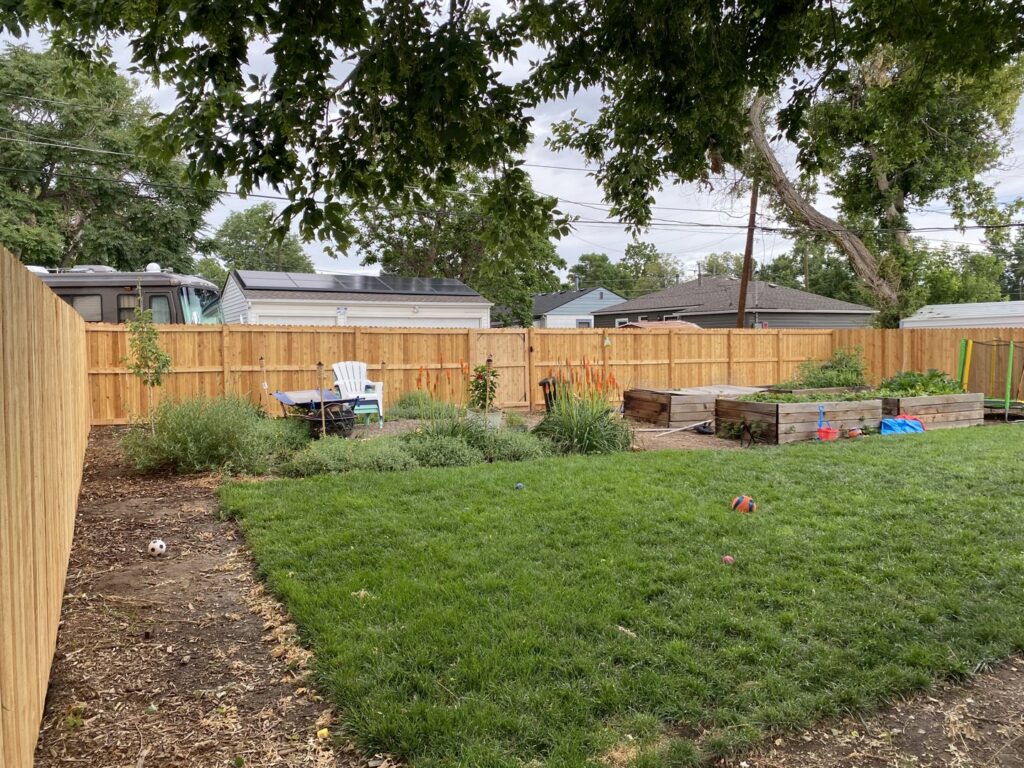 A long, sturdy wood privacy fence enclosing a spacious backyard, installed by Fence Guru LLC in Denver, CO.