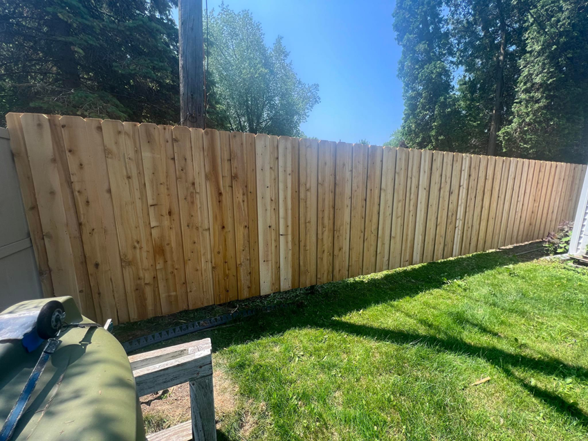 A long stretch of newly installed wood privacy fence in a sunny backyard by Northern Fence, Inc. in Appleton, WI.
