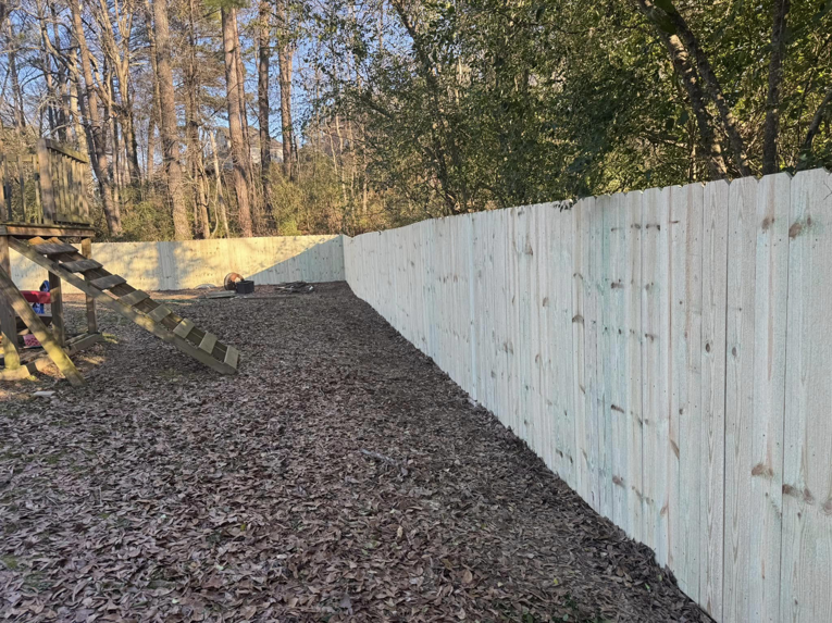 A long, newly installed wood privacy fence in a residential backyard by Precision Contracting LLC in Jupiter, FL.