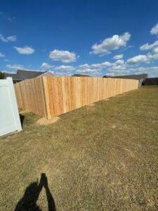 A long wood privacy fence installed in a residential backyard under a clear sky by Render Fences in Fishers, IN.