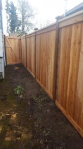 A long wooden privacy fence with a matching gate, installed along a property line by Alpine Fencing in Everett, WA.