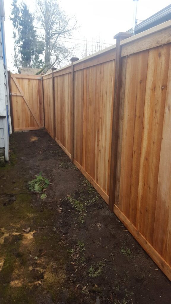 A long wooden privacy fence with a matching gate, installed along a property line by Alpine Fencing in Everett, WA.