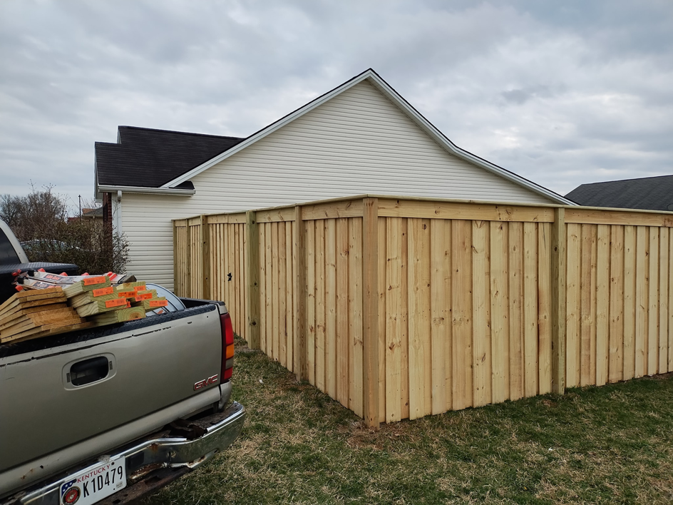 A long section of new wood privacy fence installed by Veteran Fence in North Royalton, OH, with materials nearby.