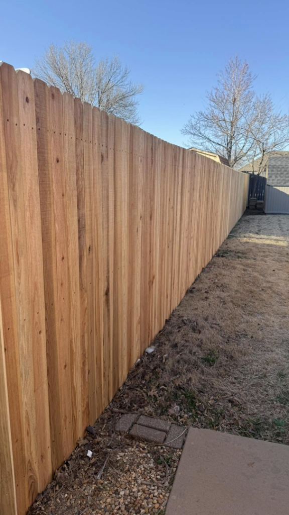 A long section of new wooden privacy fence with trees in the background by On-Guard Fencing & Gates LLC in Oklahoma City, OK.