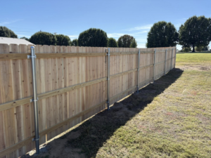 A long section of wood privacy fence with metal posts installed by McDaniel Quality Fencing LLC in Muldrow, OK.