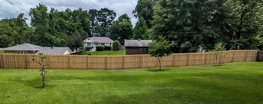 A long, newly installed wood privacy fence in a residential area by Top Rail Fence Birmingham, AL