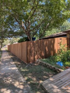A long stretch of newly installed wood privacy fence running alongside a sidewalk by EverFence in Dallas, TX.