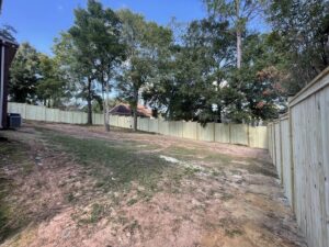 A long wooden privacy fence installed in a sloped residential backyard by Jaguar Fence LLC in Mobile, AL.
