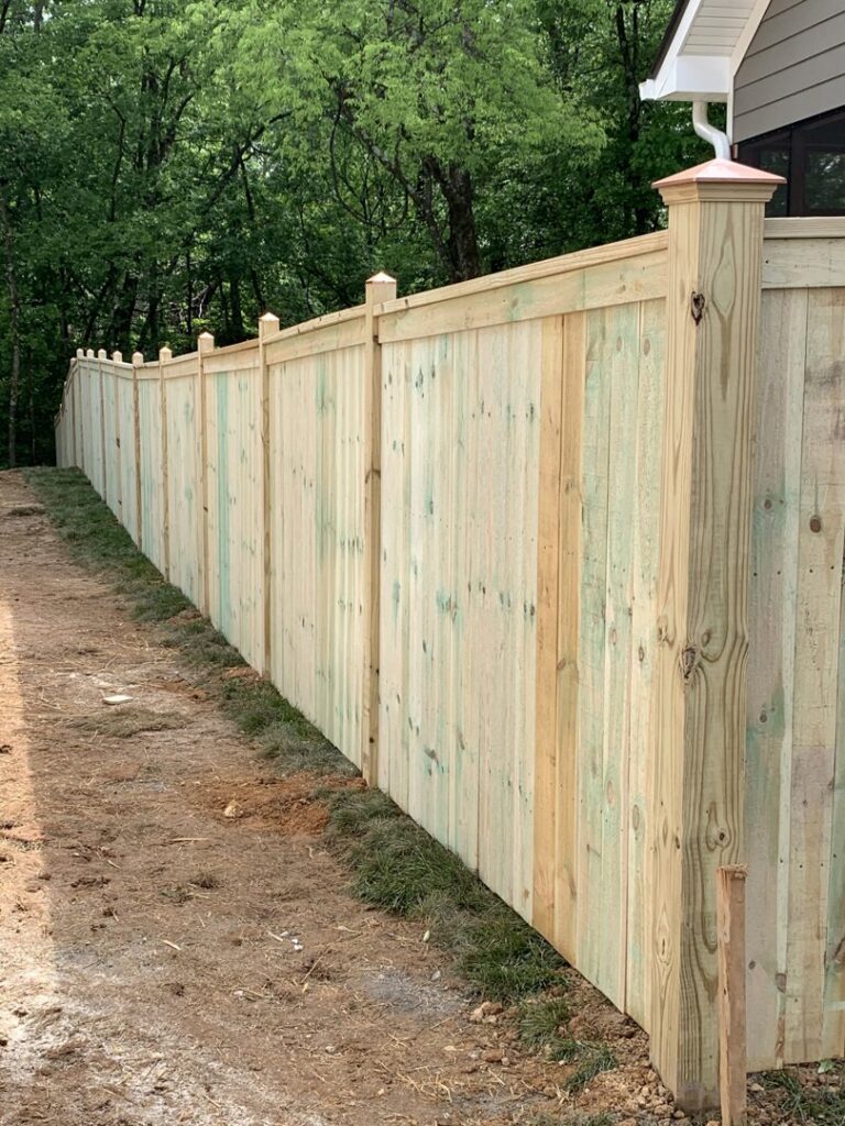 A long wood privacy fence with decorative post caps by Escamilla Fence Co. in Knoxville, TN