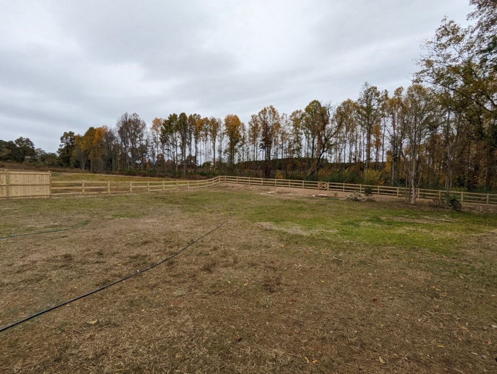 A long wooden split-rail fence installed across a large grassy property by Endurance Fence Solutions, LLC in Holly Springs, NC
