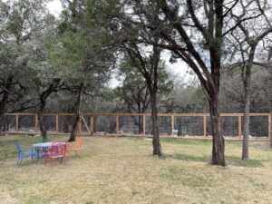 A long wood and wire mesh fence extending through a natural, rural setting by City Fence Co of San Antonio, TX