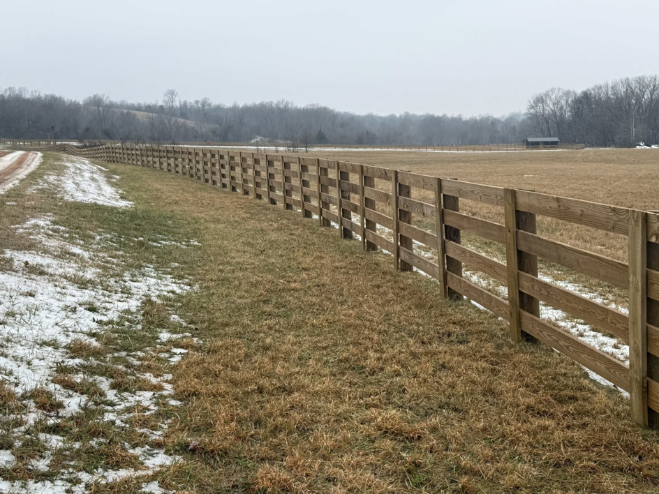 A long wooden boundary fence installed in a rural, snowy setting by Richards Fencing in Lynnville, TN