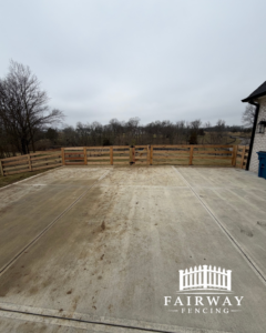 A long wooden fence line with a central gate, bordering a concrete patio, installed by Fairway Fencing in Lexington, KY.