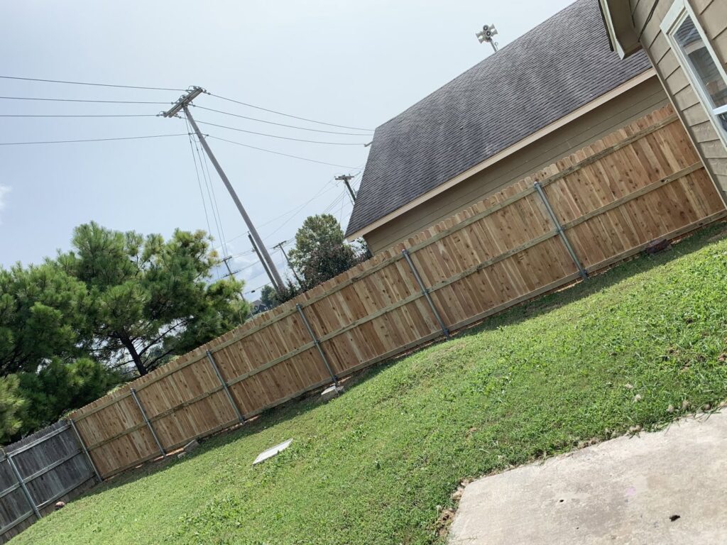 A long wooden fence expertly installed on a sloping terrain, showcasing work by Ninety-One Services in Tulsa, OK