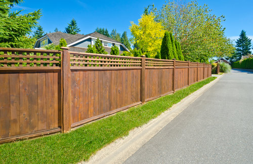A long wooden fence with a decorative lattice top section bordering a residential street, installed by Columbia Fence Co. in Columbia Station, OH.