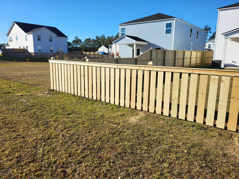 A long stretch of newly installed wooden picket fence in a backyard by Lundquist Home Improvements in Mount Pleasant, SC.