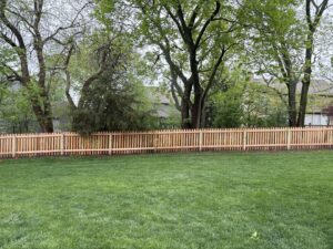 A long wooden picket fence installed in a residential backyard by Pride Fence in Peabody, MA.