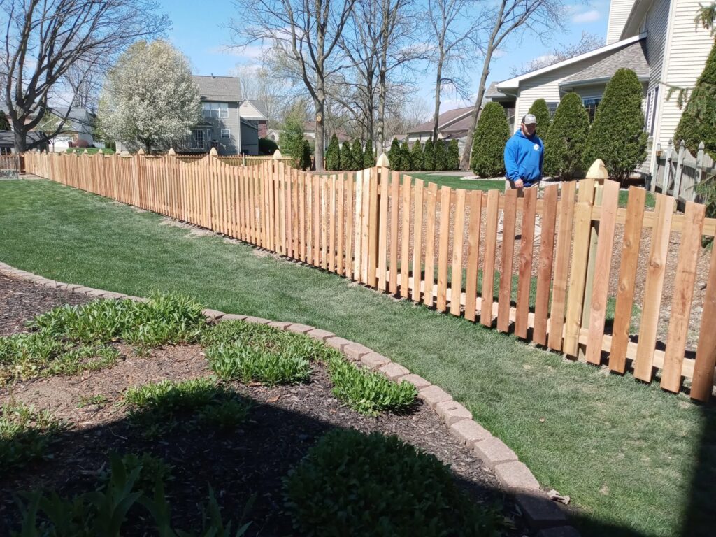 A long wooden picket fence installed in a residential backyard, showcasing quality work by Sparta Fencing in Ely, UK.