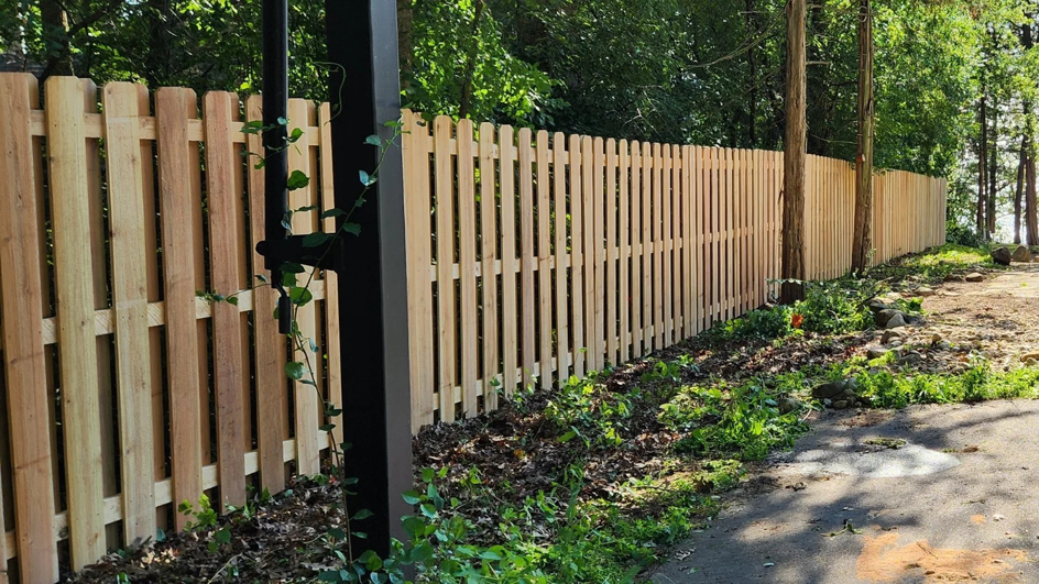 A long wooden picket fence installed along a residential property by Browning & Sons Fencing, Home Renovations, and More in Suwanee, GA.