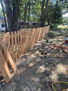 A long wooden picket fence installation project by Fianna Fencing Company in Fort Smith, AR, with tools nearby.