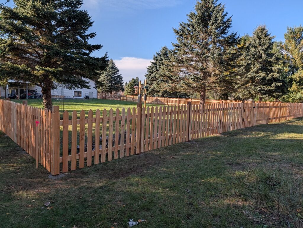 An extensive wooden picket fence enclosing a spacious residential yard by Top Notch Fence in East Bethel, MN