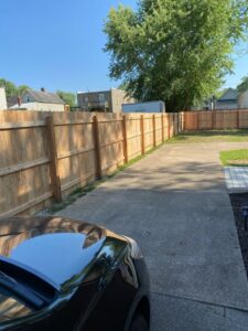 A long wooden privacy fence providing boundary along a driveway, installed by Petty Fence Company LLC in Evansville, IN.