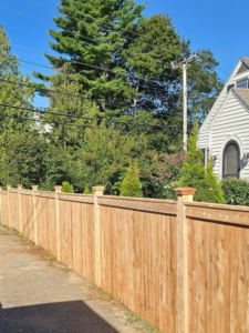A long wooden privacy fence installed along a sidewalk by Midcoast Fence in Northport, ME.