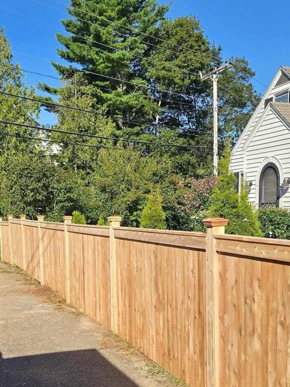 A long wooden privacy fence installed along a sidewalk by Midcoast Fence in Northport, ME.